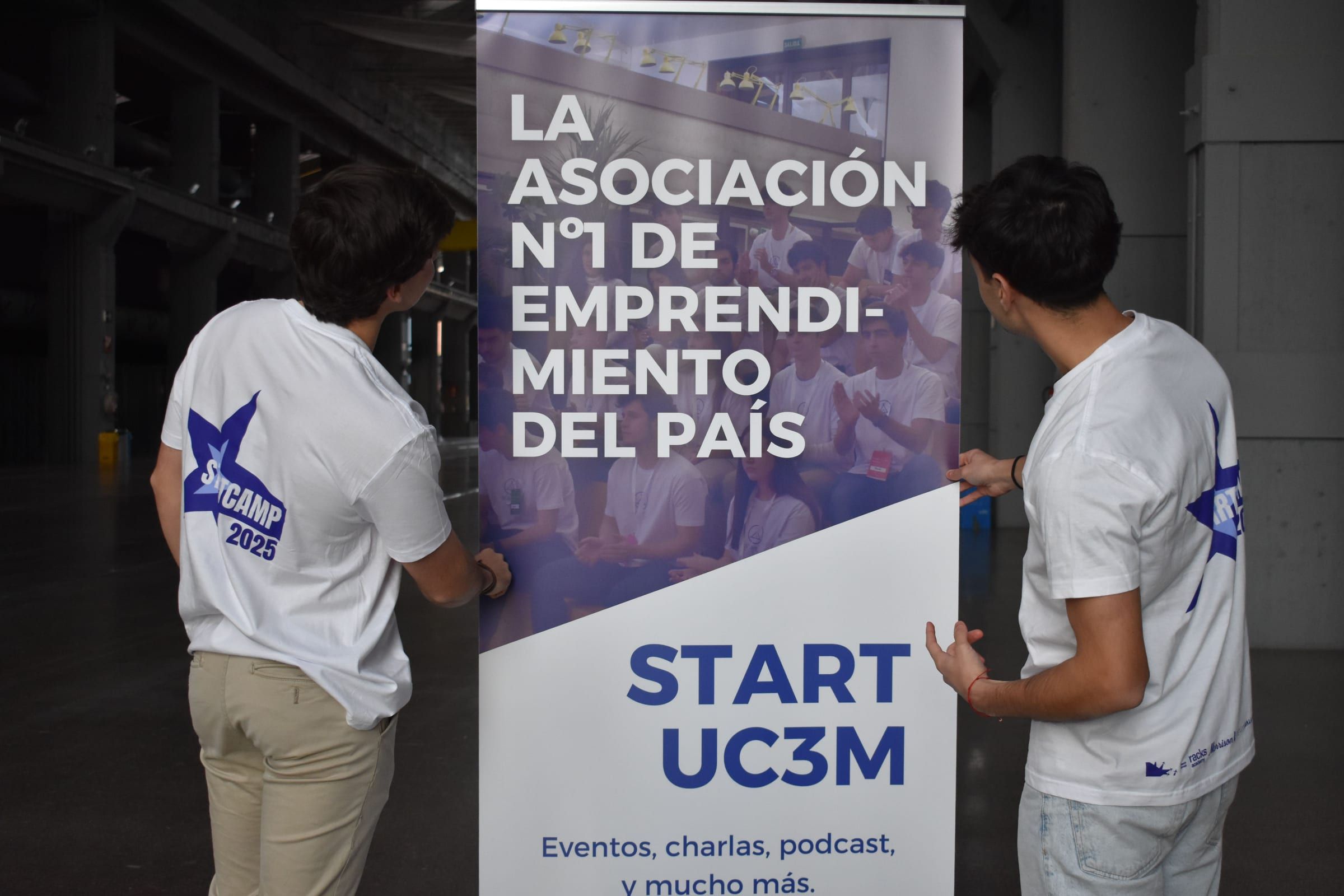 Dos miembros del staff del Start Camp 2025 colocando el roll-up de Start UC3M: la asociación nº1 de emprendimiento del país